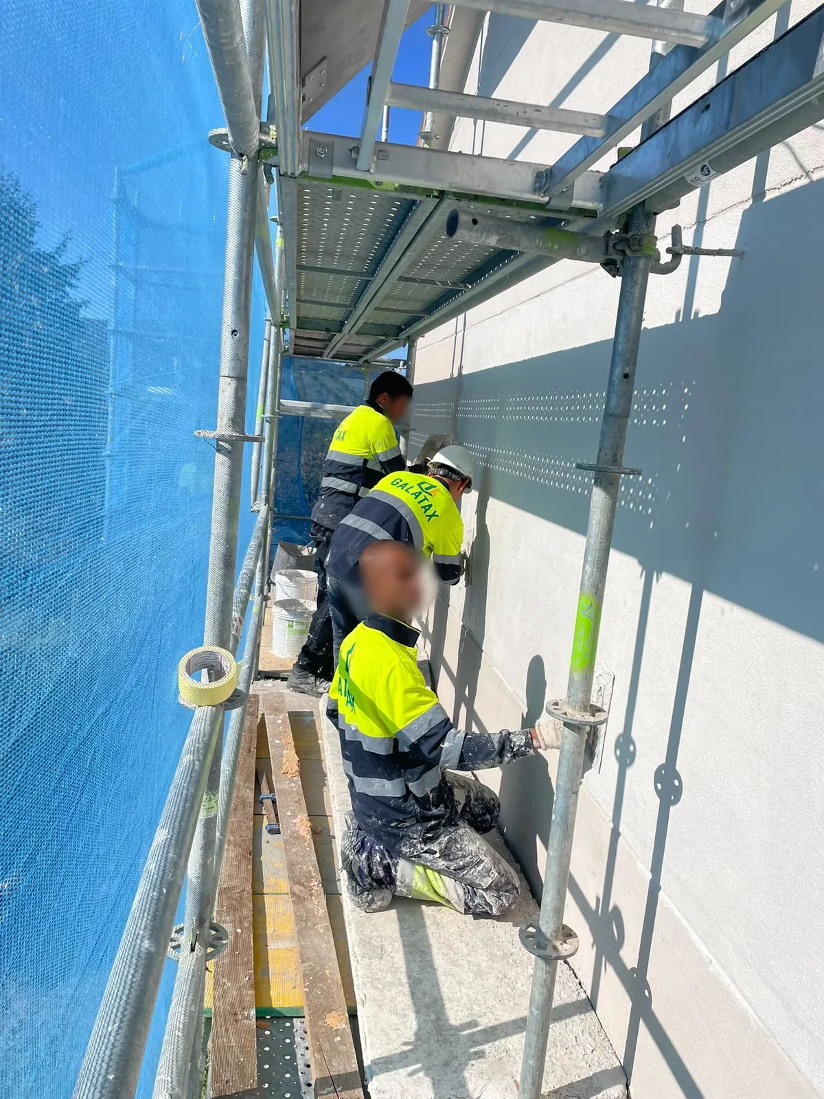 Operarios de Construcciones Galatax aplicando mortero en una fachada desde el andamio