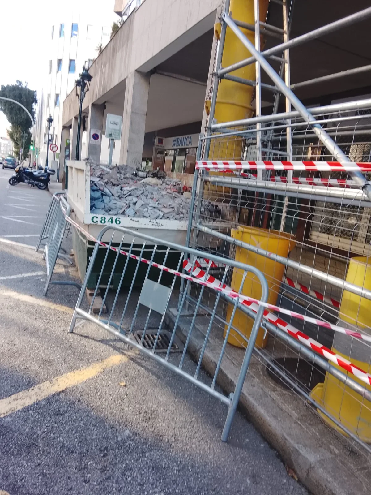 Demolición en local comercial con contenedor de escombro y vallado en Vigo