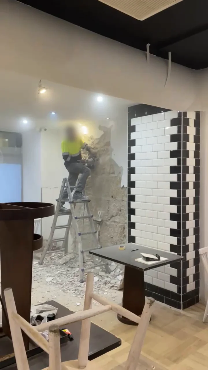Demolición del revestimiento de una pared durante la reforma de un local