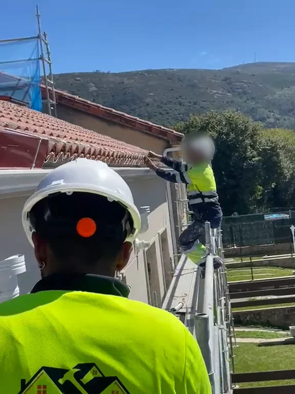 Operario trabajando en una cubierta de teja cerámica desde el andamio