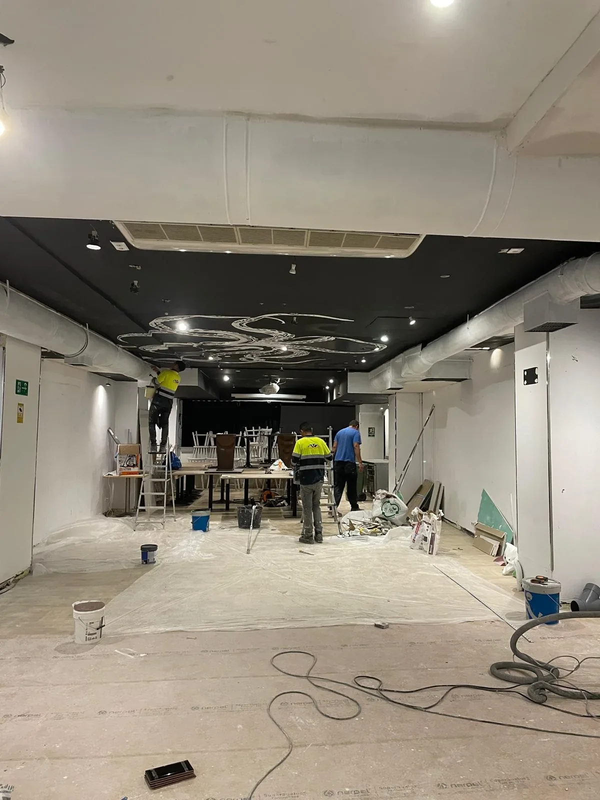 Local de restaurante durante la reforma, con el equipo trabajando en techos e instalaciones